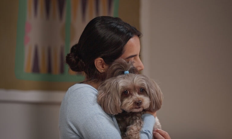A woman hugging her dog with tear stains