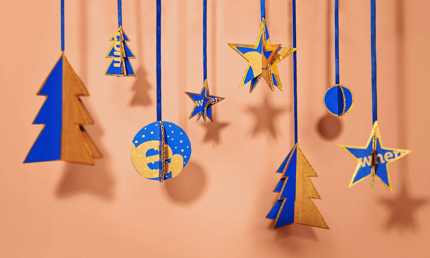 Photo of Christmas ornaments made from Chewy boxes hanging in front of a peach-colored backdrop