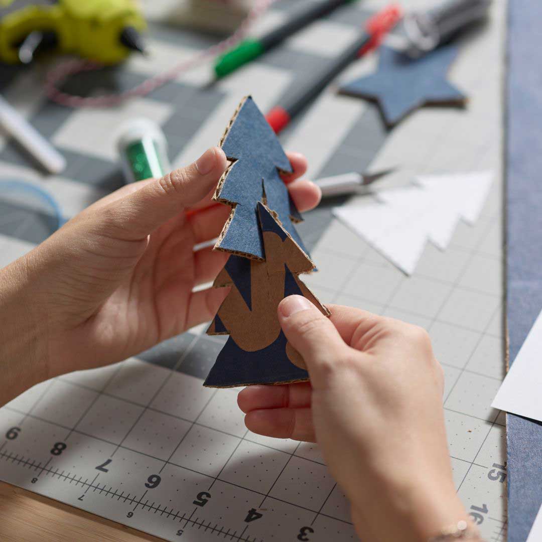 Photo of hands assembling DIY Christmas ornaments made from Chewy boxes