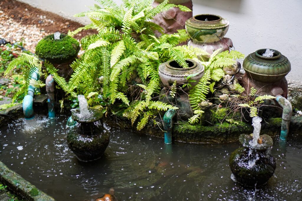 Small backyard garden pond featuring decorative water fountains for aeration.