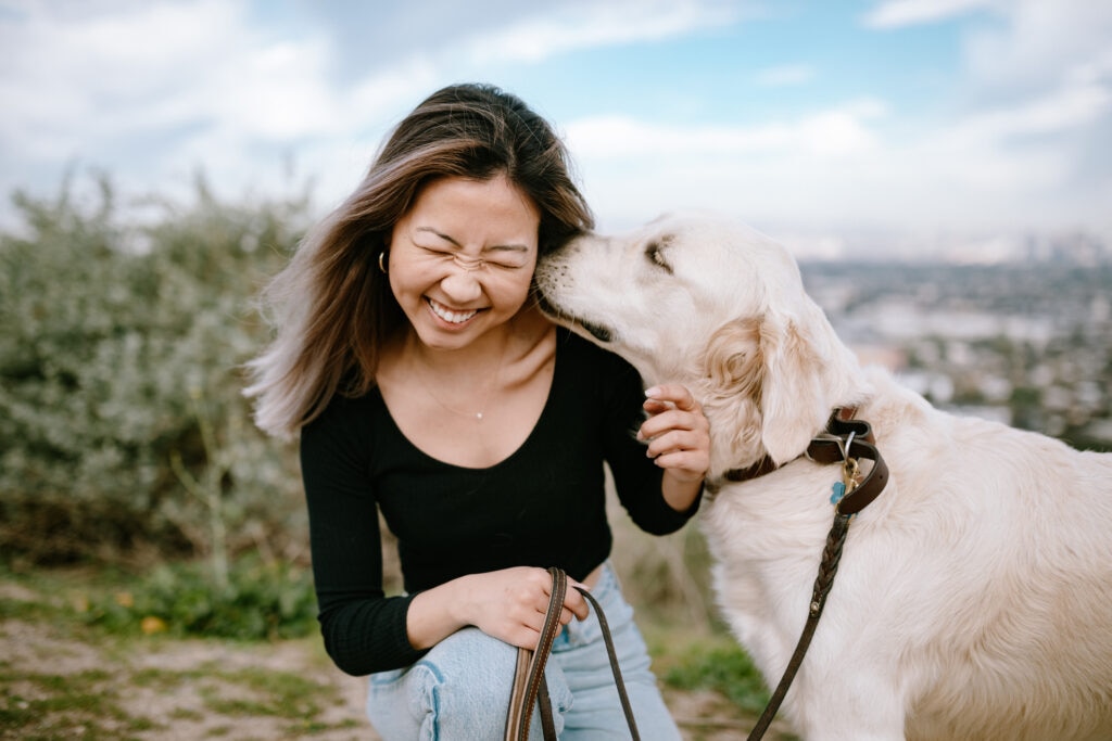 Photo of a woman snuggling her dog near a beach, one of the top things to do with your dog in 2025