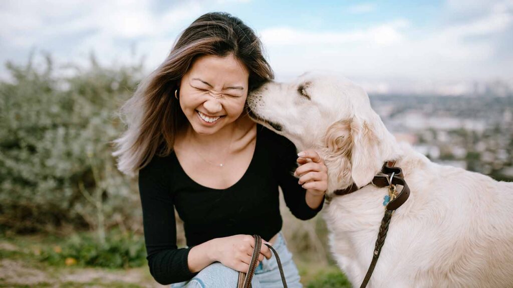 woman snuggling her dog near a beach, one of the top things to do with your dog in 2026