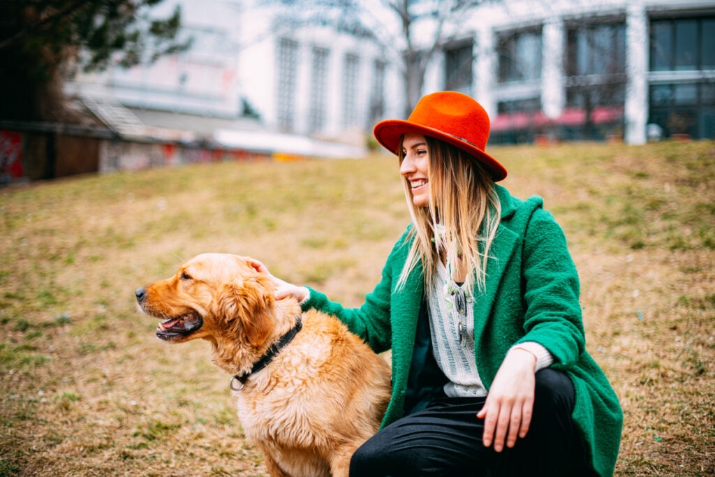 woman-sitting-with-golden-retriever-in-sand