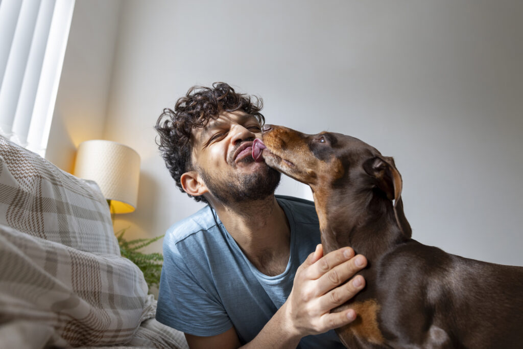 man being kissed by dog on his face.