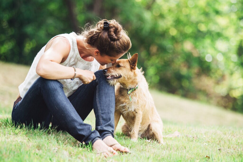 woman-sitting-in-grass-with-dog