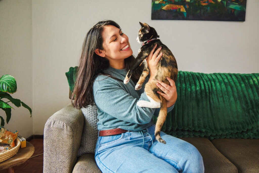 woman-holding-up-cat-sitting-on-couch