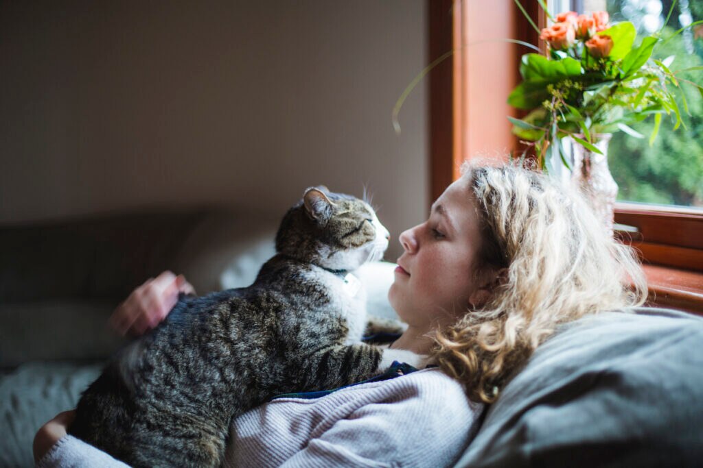 woman-sitting-on-couch-with-cat-on-chest