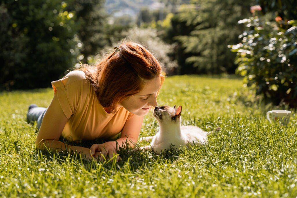 can humans get tapeworms from cats; a pet parent sits with their cat on the grass.