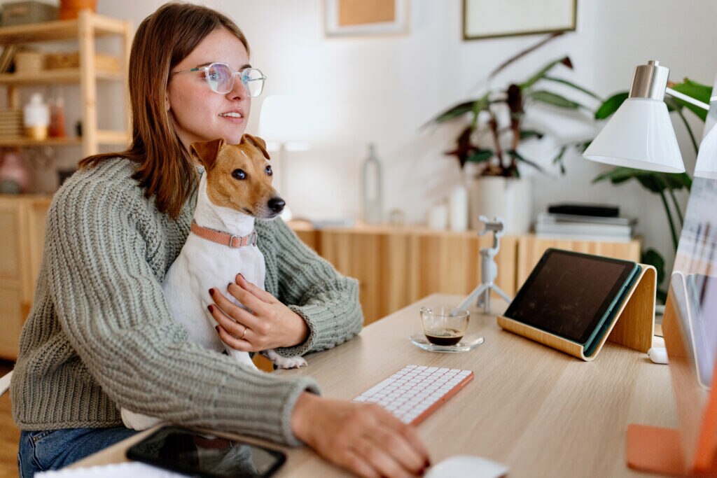 A pet parent sits with her dog during an online vet appointment.