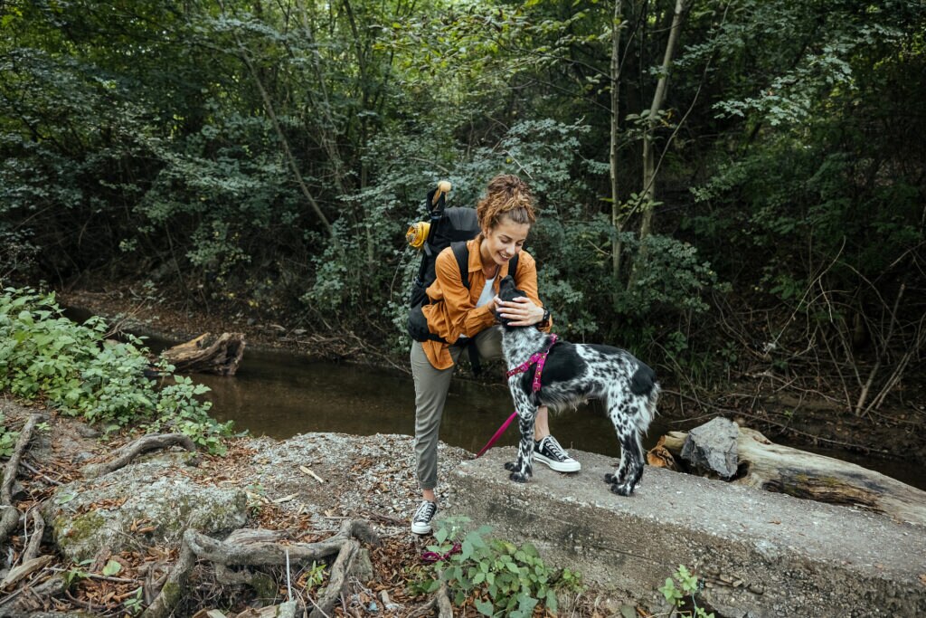 best dog hiking gear; a woman hikes with her dog across a rocky terrain.