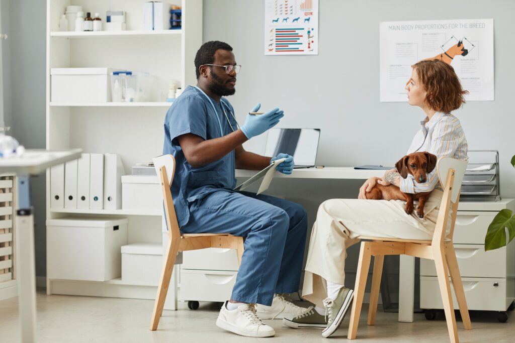 vet talking to pet parent while holding dog in office