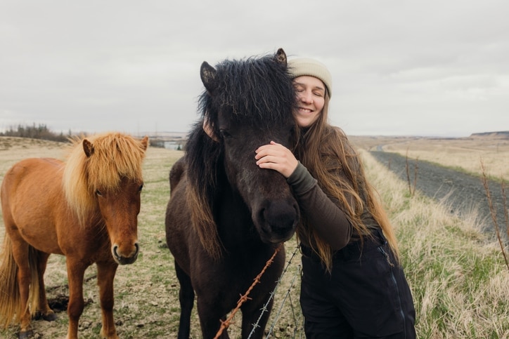 woman cuddling an icelandic horse outside
