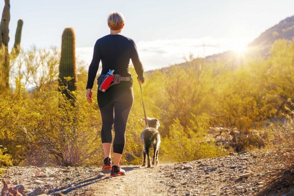 woman walking dog through a desert at sunrise