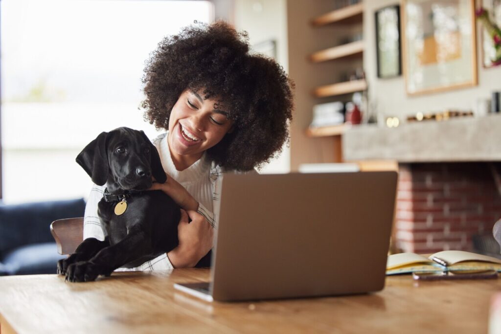 african-american-woman-sitting-in-front-of-laptop-with-puppy