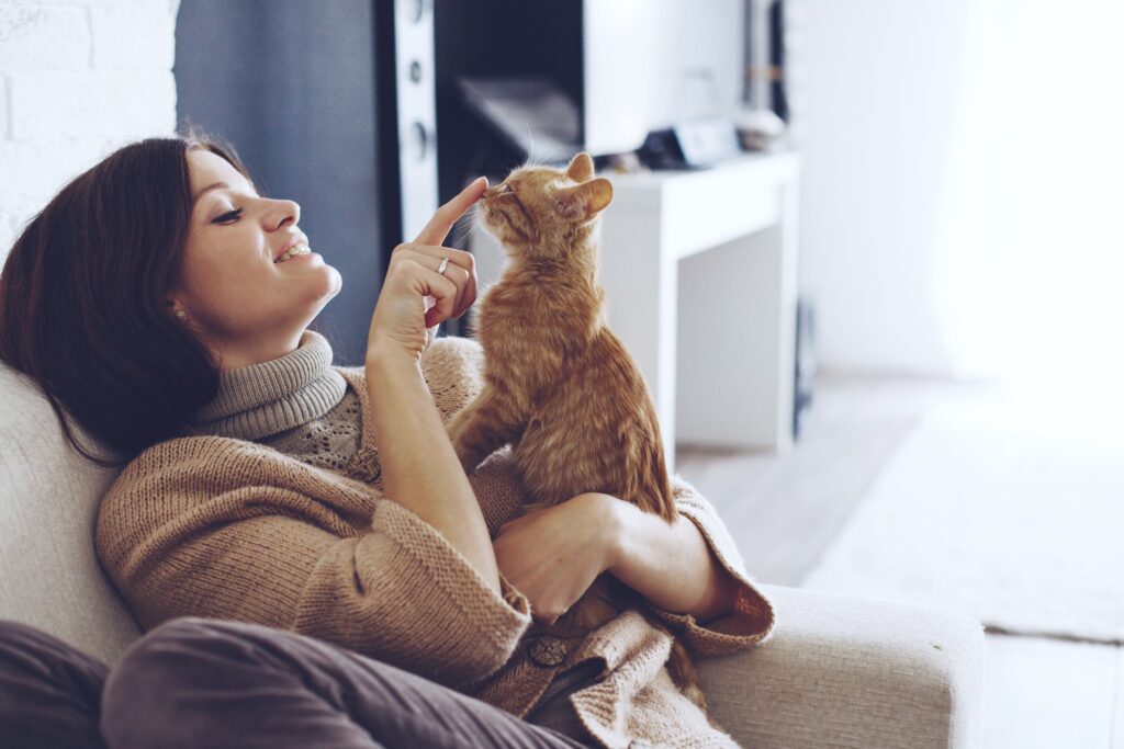 woman cuddling an orange kitten on the couch