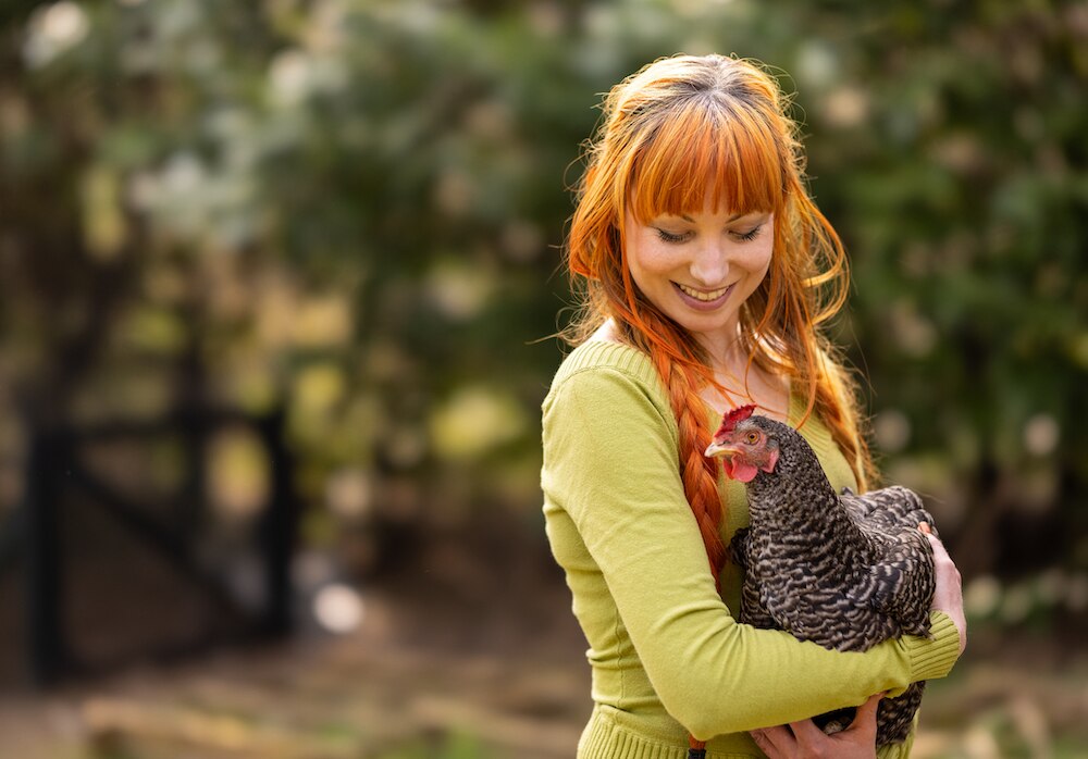 Red-haired woman holding chicken