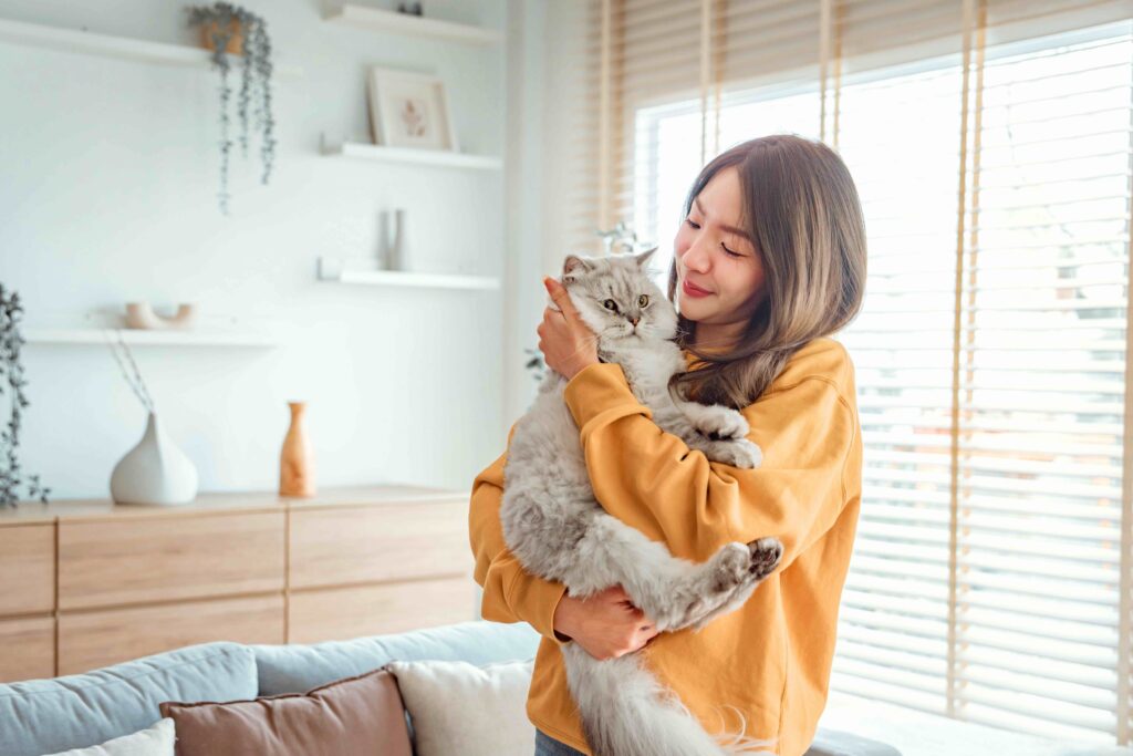 woman holding a longhaired silver cat in her apartment