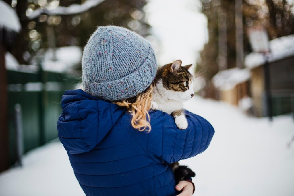 A pet parent holds her cat on a cold day.