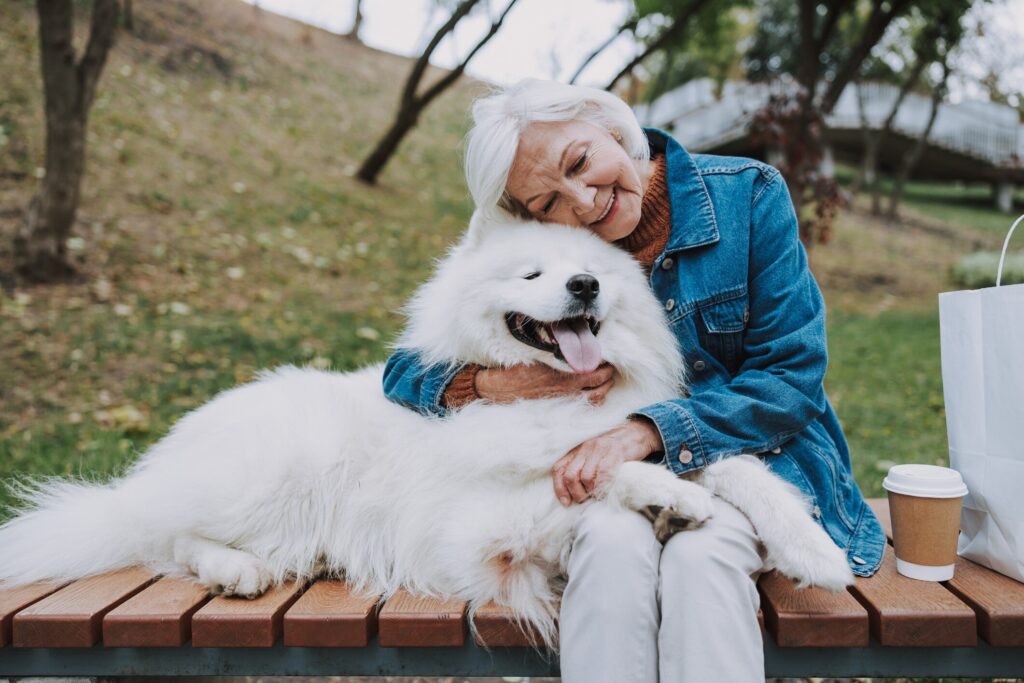 woman hugging a fluffy white dog on a bench