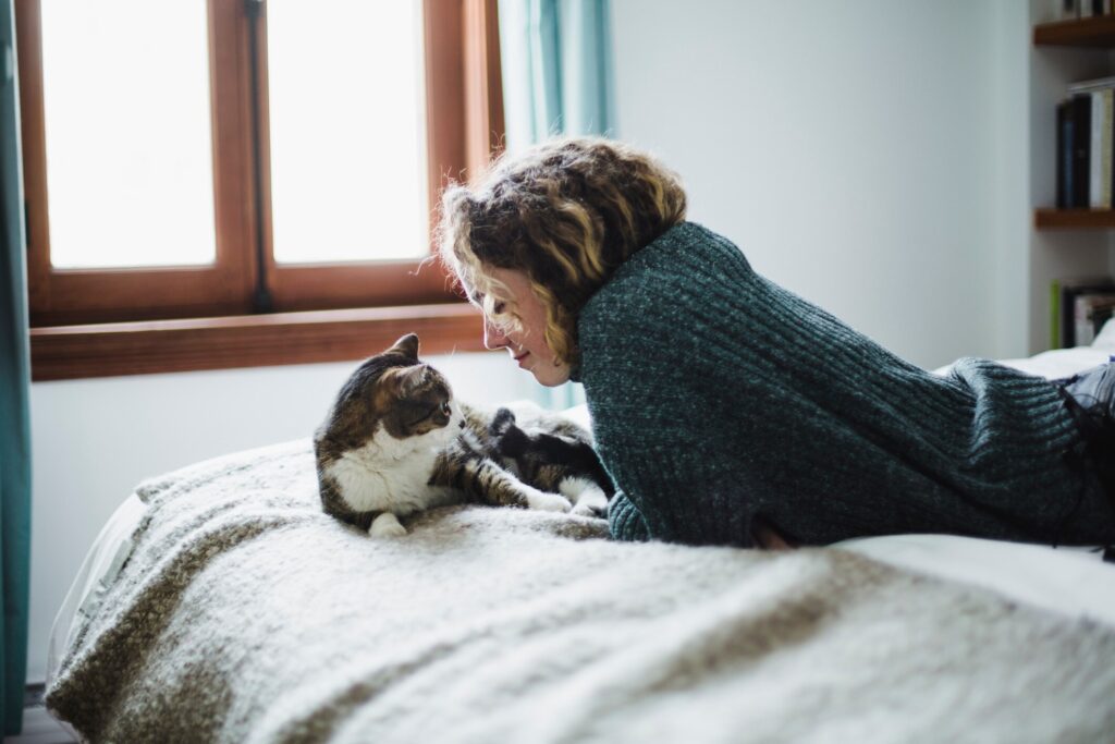 woman lying on a bed with a white and brown tabby cat