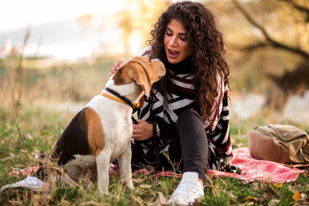 woman crouched on the ground and talking to a beagle