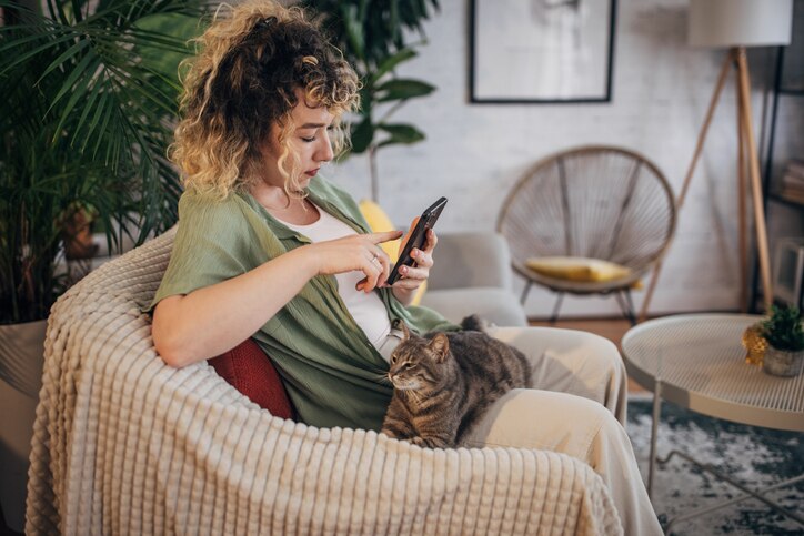 how long do fleas live without a host; woman scrolling on phone with cat in lap