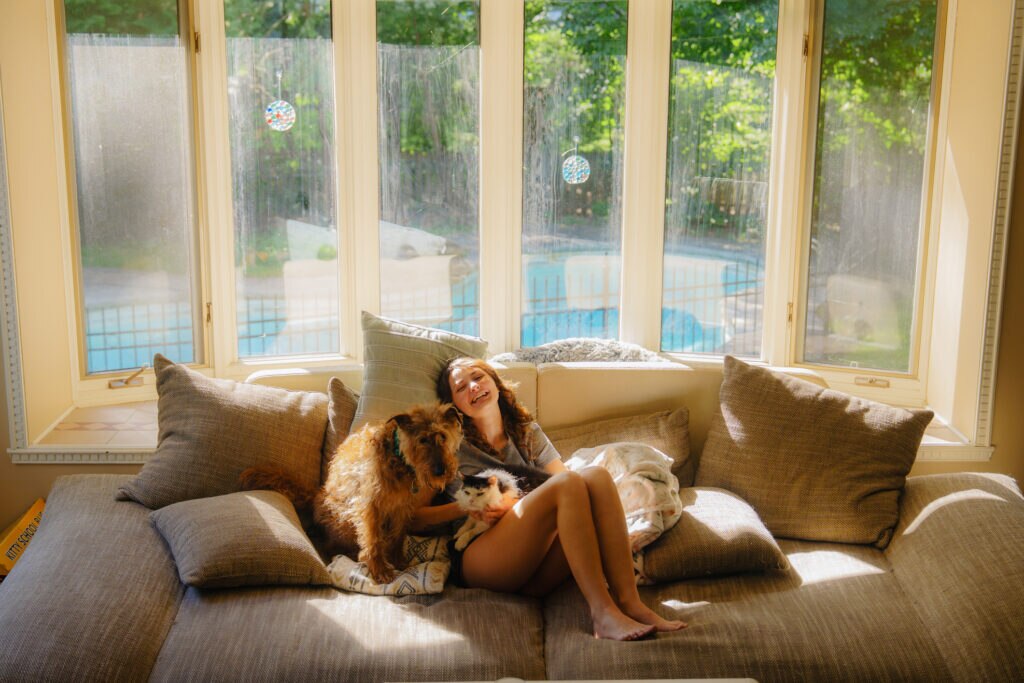 woman experiences the human-animal bond through cuddling her dog and cat.