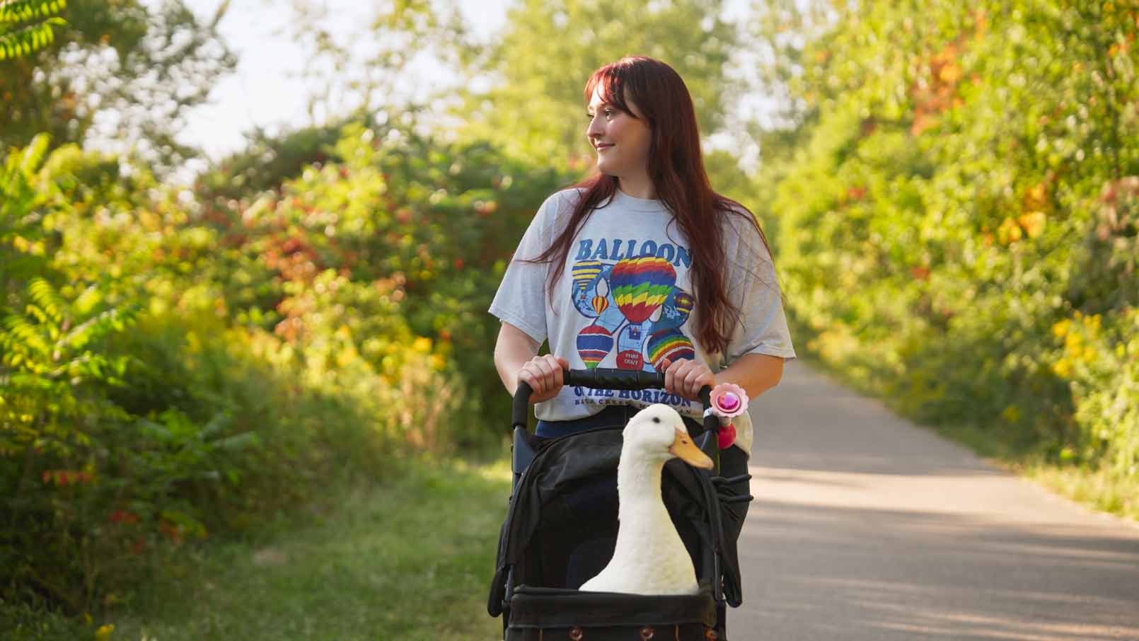 Aspen pushes Fern in a stroller through a park