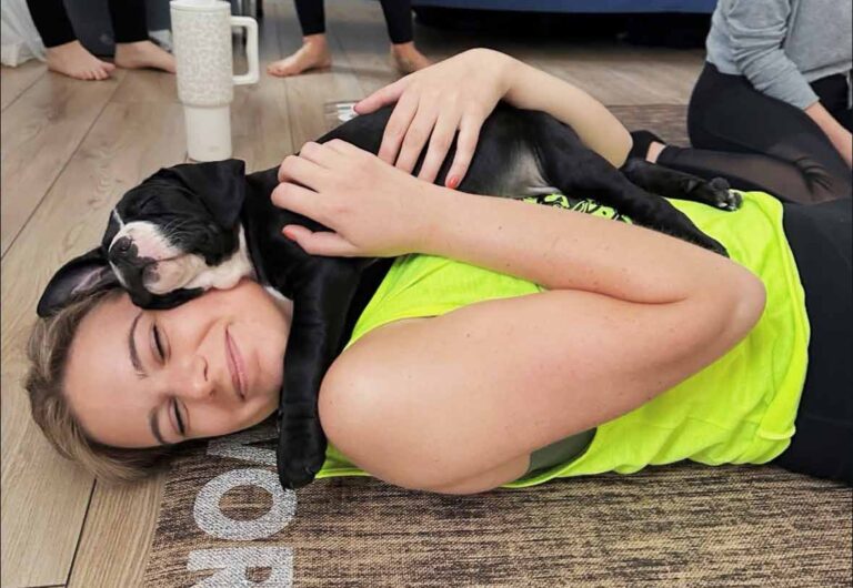 A woman snuggling a puppy during puppy yoga