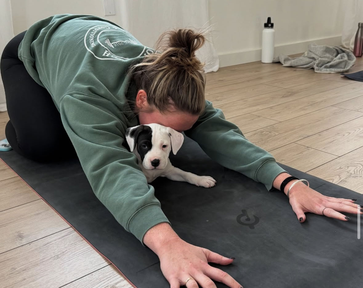 woman practicing yoga with puppy