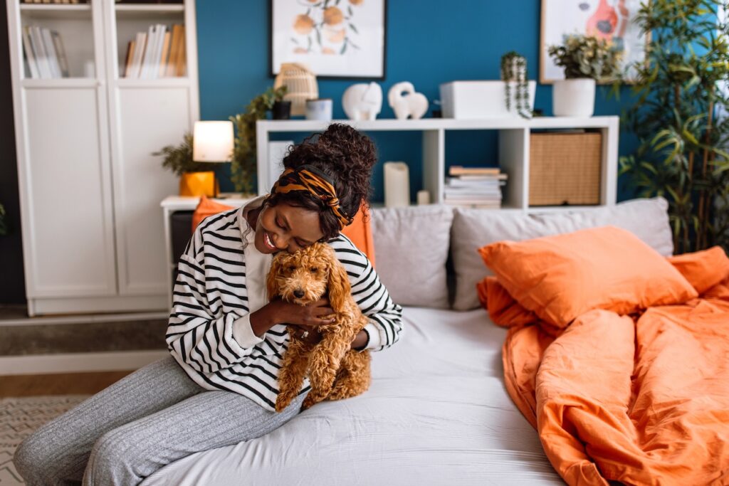 a woman hugging a doodle dog on her bed. Learn what causes pet allergies