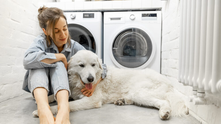 A woman sitting with her dog in their laundry room