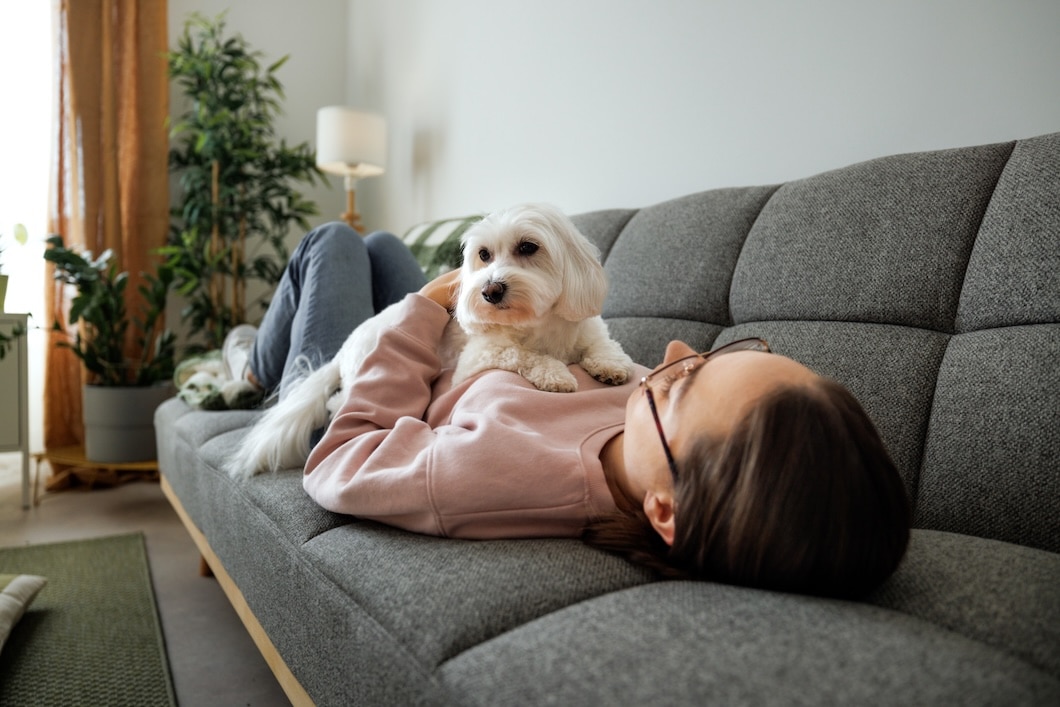 Young girl relaxing on a bed with a Maltese dog.
