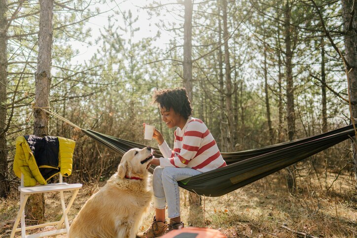 A woman camping with her dog, a Golden Retriever.