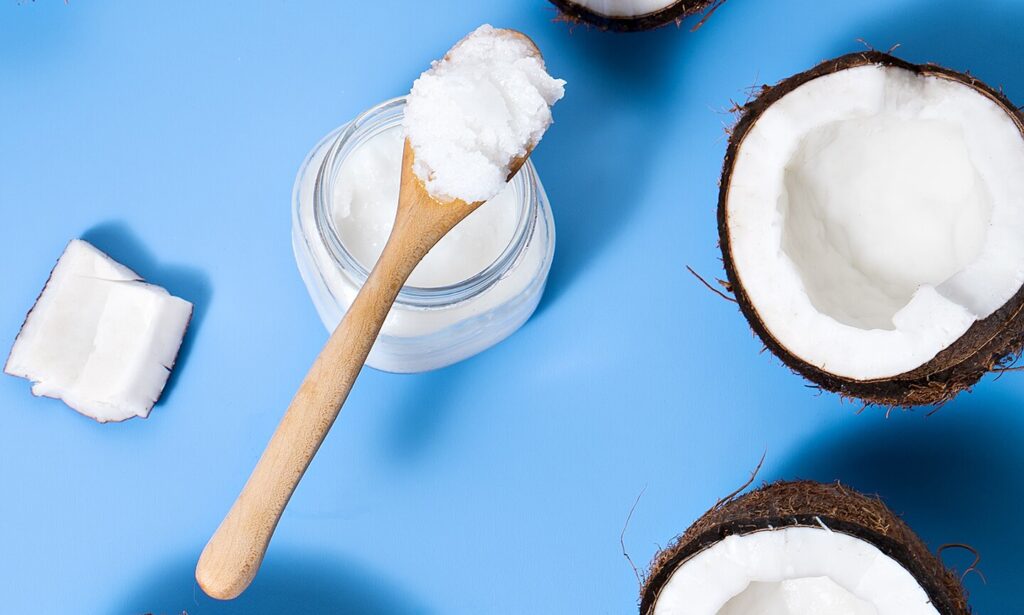 coconut oil for cats: coconut oil in jar with spatula against blue background
