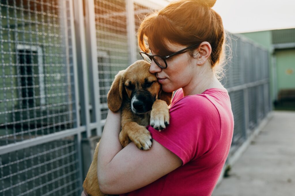 woman holding and hugging a brown puppy