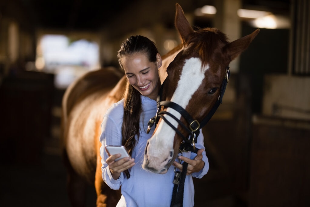 vet-looking-at-phone-next-to-horse