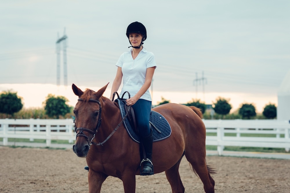 Woman riding a horse beginner first riding lesson